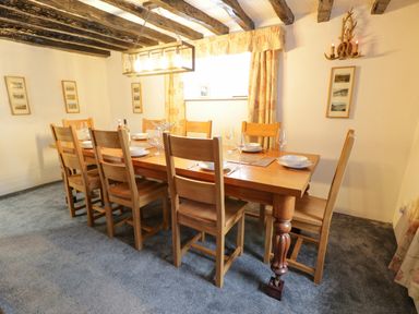 A dining room with wooden table and chairs set for dinner at Cae Lleci in Llanfachreth near Dolgellau