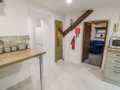 A kitchen area with a wooden countertop containers a microwave and a fire extinguisher on the wall at Cae Lleci Llanfachreth near Dolgellau