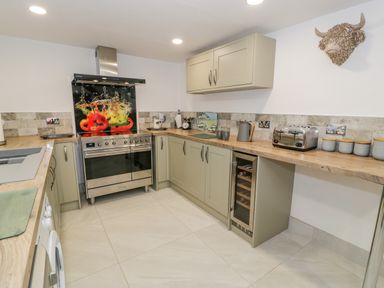 A kitchen with a stove oven a wine cooler a toaster and cabinets at Cae Lleci Llanfachreth near Dolgellau