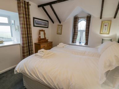 A bedroom with two single beds a wooden dresser with mirror and plaid curtains at Cae Lleci Llanfachreth near Dolgellau