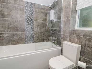 A bathroom with a bathtub shower combination and a toilet at Cae Lleci Llanfachreth near Dolgellau