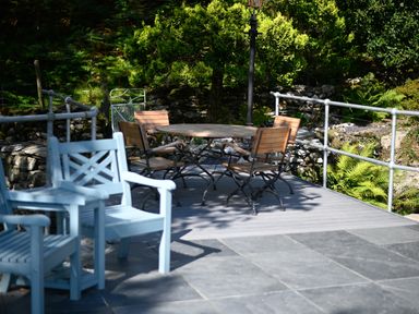 An outdoor patio with wooden chairs and a round table surrounded by metal railings at Cae Lleci Llanfachreth near Dolgellau