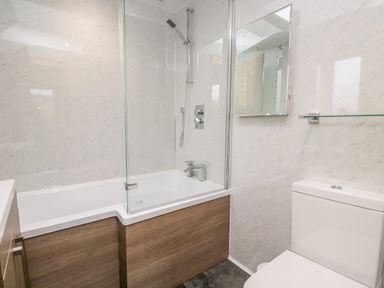 A bathroom with a bathtub shower combination and toilet at La'al Riddings Lowick Green Riddings Farm Near Ulverston