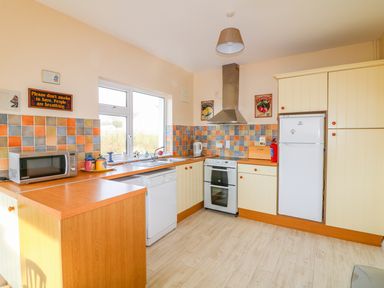 A kitchen with wooden countertops a microwave dishwasher stove refrigerator and multicolored tiled backsplash at The Trawler in Blackwater County Wexford