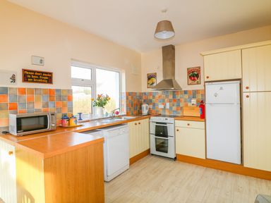 A kitchen with a microwave oven dishwasher stove and refrigerator with a window above the sink at The Trawler in Blackwater County Wexford