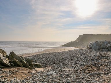 A rocky beach with waves in the sea and cliffs in the background at The Trawler in Blackwater County Wexford