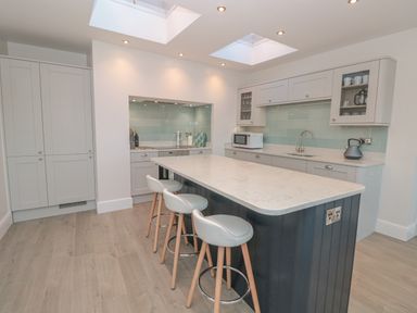 A kitchen with a large island and three stools under skylights at Moorings in Kingswear Devon