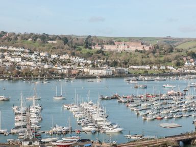 A marina with boats and yachts on the water with houses and hills in the background at Moorings in Kingswear Devon