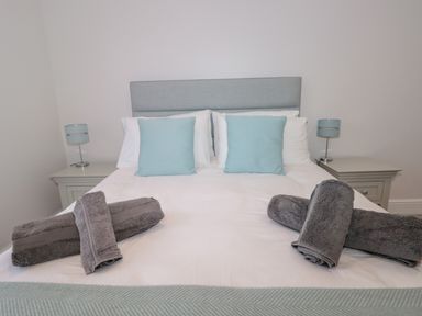 A bedroom with a double bed with blue cushions and gray towels on the bed at Moorings in Kingswear Devon