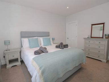 A bedroom with a double bed bedside tables lamps a chest of drawers and a mirror at Moorings in Kingswear Devon