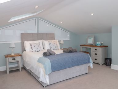 A bedroom with a bed side tables lamps and a dressing table with mirror at Moorings Kingswear Devon