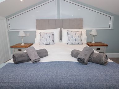 A bedroom with a double bed two bedside tables lamps and rolled towels at Moorings in Kingswear Devon