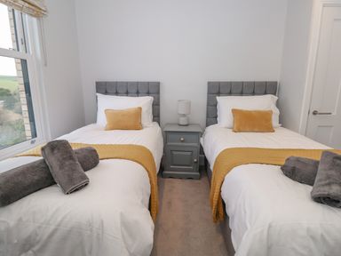 A bedroom with two single beds and a nightstand with a lamp between them at Moorings in Kingswear Devon