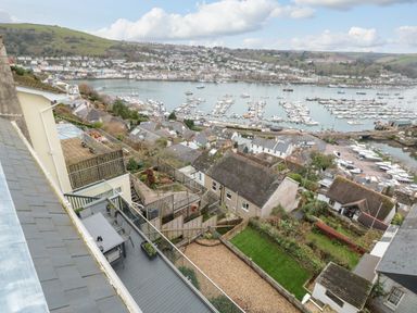 A hillside view overlooking rooftops gardens and a marina with boats in Kingswear Devon