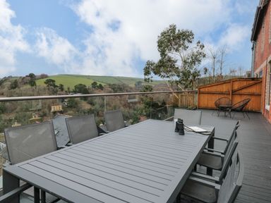 An outdoor terrace with a dining table and chairs overlooking trees and hills at Moorings in Kingswear Devon