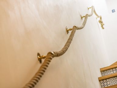 A staircase with wooden steps and patterned risers with a rope handrail attached to the wall at West Cliff Apartment in Whitby