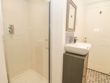 A bathroom with a shower enclosure sink with faucet mirror and patterned floor tiles at West Cliff Apartment in Whitby