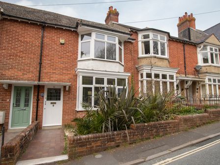 A street view of row houses with brick walls and bay windows with plants in front at Sandsfoot Rest in Weymouth