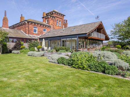 A garden with shrubs and outdoor seating by a house with large windows and a balcony at Villa Marina in Roa Island
