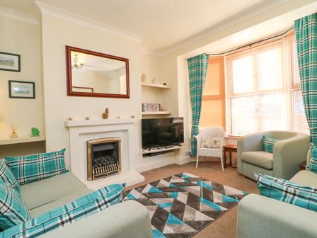 A living room with sofas a patterned rug a TV and a fireplace at Brewers House in Weymouth