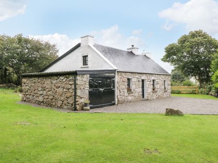 A stone cottage with a slate roof and green grass surrounding it at An Teach Ban in Rossaveel County Galway