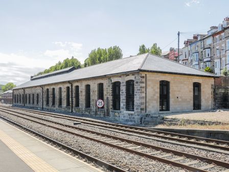 A stone building with arched windows next to railway tracks at Evening Star @ Engine Shed in Whitby