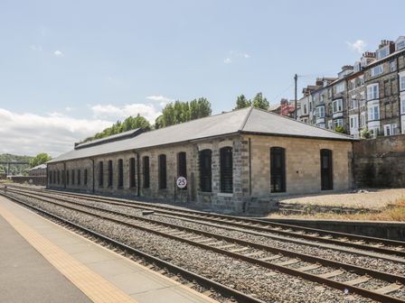 A stone building with multiple windows beside railway tracks at George Stephenson @ Engine Shed in Whitby