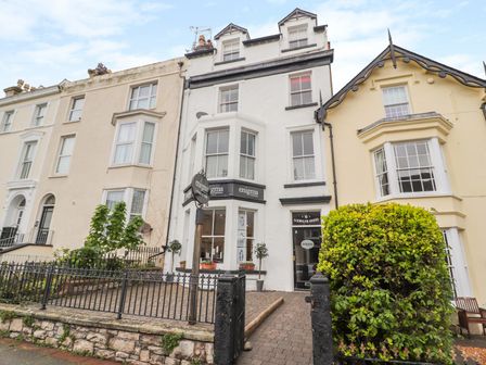 A row of multi-story buildings with a sign for enigma outside Llewelyn House in Llandudno
