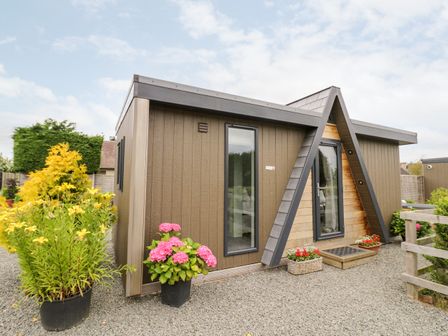 Exterior view of a small wooden building with plants and flowers outside at Hydrangea in Bretforton