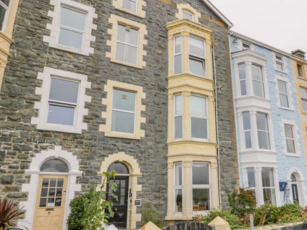 The front view of a row of stone houses with multiple windows and doors at Abermaw Views in Barmouth
