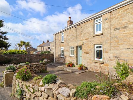 Stone cottage with a front garden and potted plants by the door at Chy Lowena in Pendeen