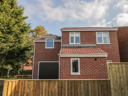 A brick house with three windows garage door and a wooden fence at Hawthorn in Whitby