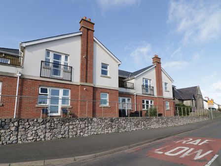 A street view of two connected houses with chimneys and balconies at Bay View in Benllech