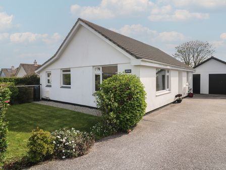 A white single-story house with a pitched roof and garden at Tremar in Carbis Bay