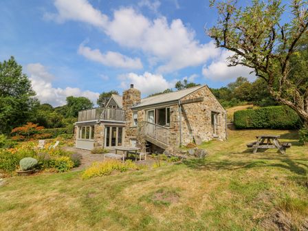 A stone house with outdoor seating and garden area at Plasybangor in Newport Pembrokeshire