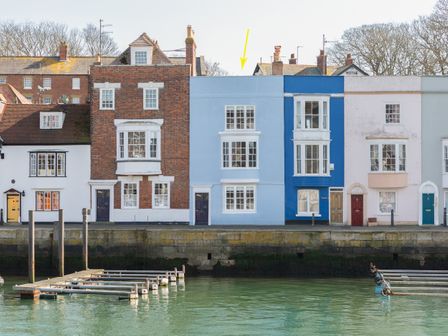 A row of colorful waterfront houses with docks in front at The Boat House in Weymouth