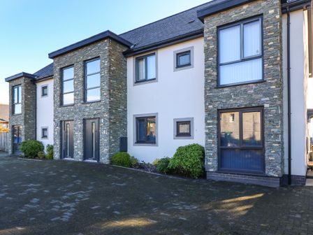 Exterior view of a modern two-story building with stone and white walls and black framed windows at Cysgod Y Capel in Benllech