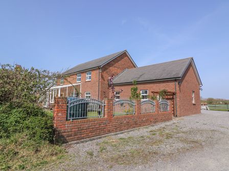 A two story brick house with a gray roof and a brick and metal fence in front at Cadwgan in Aberporth