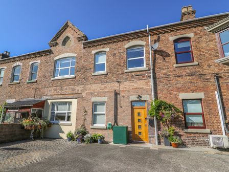 A brick exterior building with multiple windows a wooden door and potted plants at Ty'r Orsaf in Builth Wells