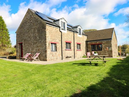 A stone house with solar panels and outdoor furniture at Milking Shed near Narberth