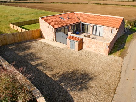 A single story brick house with a red tiled roof and gravel driveway in a rural area at Owl View in Lebberston near Cayton