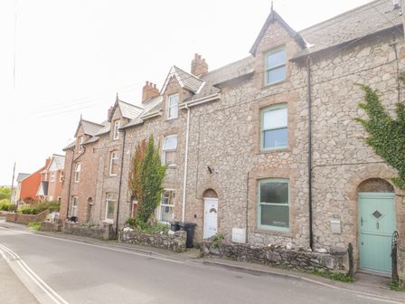 A row of stone terraced houses with chimneys and small front gardens on a street at 30 West Street in Watchet