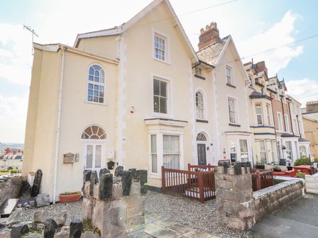 A row of terraced houses with small front yards and stone walls at Tram View in Llandudno