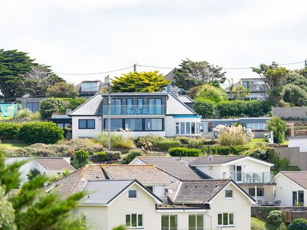 A view of multiple houses on a hillside with trees and bushes at Blue Bay Beach House in Mawgan Porth