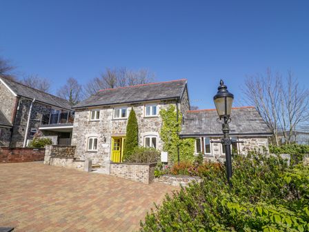 A stone house with a yellow door and a street lamp in front at Cornflower Cottage in St Columb Major