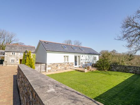 A stone and white house with a patio and lawn surrounded by a stone wall at Forget-me-not in St Columb Major