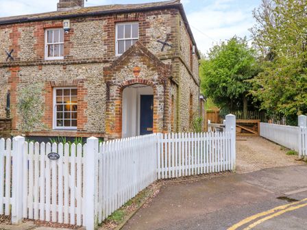 Exterior of a stone and brick house with white picket fencing and a gravel driveway at 3 Station Cottages in Wymondham