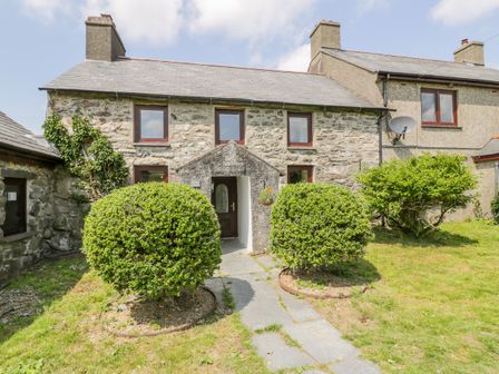 A stone exterior of a house with a pathway and round bushes in front at Bwthyn Pennant in Porthmadog