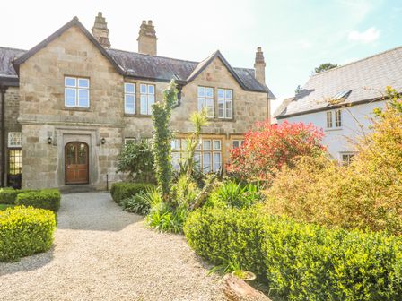 A stone house with a gravel path and garden plants at Surf Song in Penzance