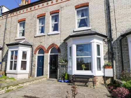 The exterior of a brick townhouse with two bay windows blue and black doors and potted plants outside at Sailors Lodge in Filey
